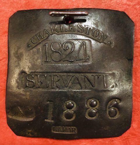 Image of a square shaped copper tag stamped with the text "Charleston 1824 Servant 1886 Lafar"